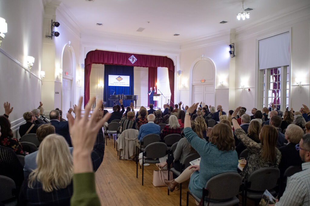 Audience members raise their hands to participate in the interactive portion of Kim's keynote speech