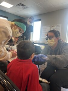 A dental student conducts a basic oral health screening on a young patient. 